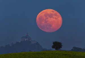 „Superúplněk“ vychází za hradem Kunětická hora na Pardubicku. Vjem velkého Měsíce vůči hradu je důsledkem perspektivy. Načervenalá barva je způsobena zeslabením měsíčního svitu procházejícího zemskou atmosférou. Foto: Petr Horálek.